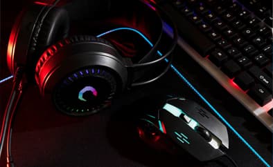 Gaming headset beside a backlit keyboard and mouse